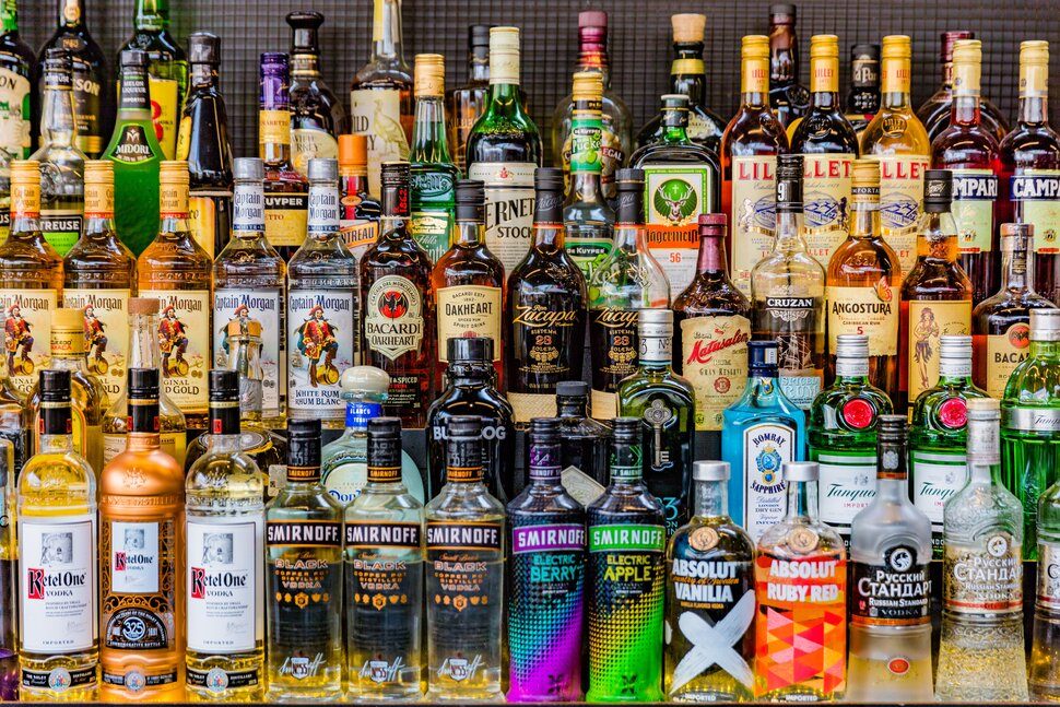 Rows of assorted spirits bottles lined up across backlit bar shelves